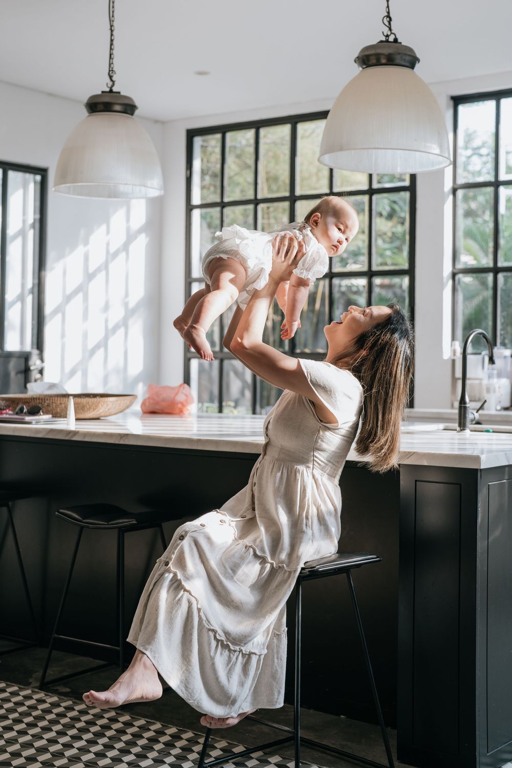 A family plays together in a modern kitchen with black cabinets and large windows.
