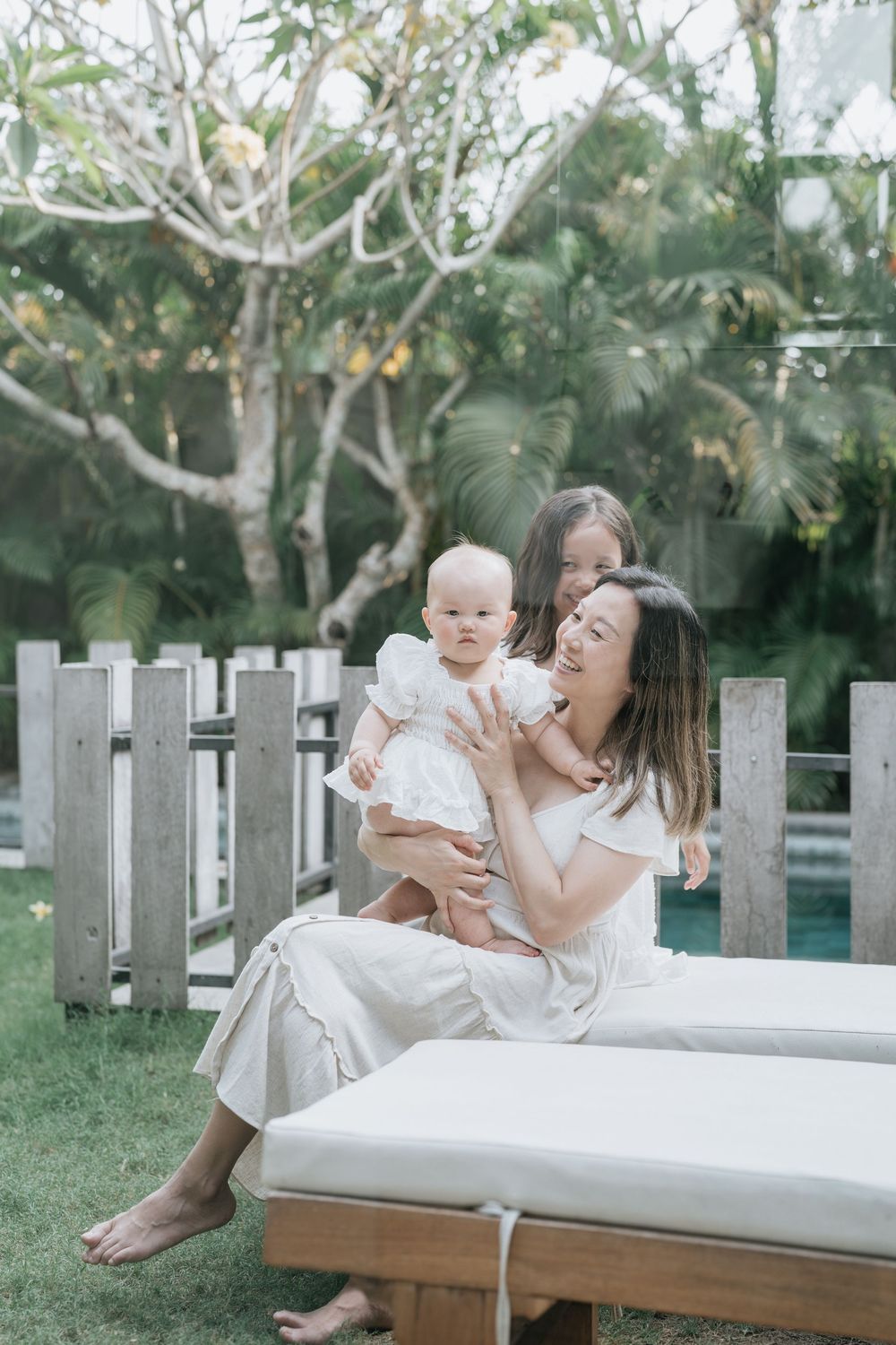Family sharing tender moments on white outdoor furniture surrounded by garden landscaping.