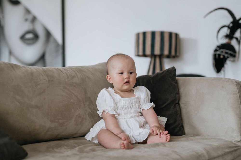 Contemporary living room setting with baby on beige couch and fashion wall art.