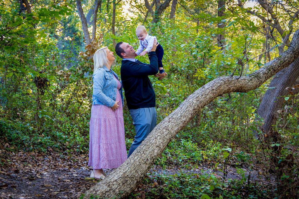 A romantic couple in a wooded area poses for a series of sweet and intimate engagement photos near a fallen tree.