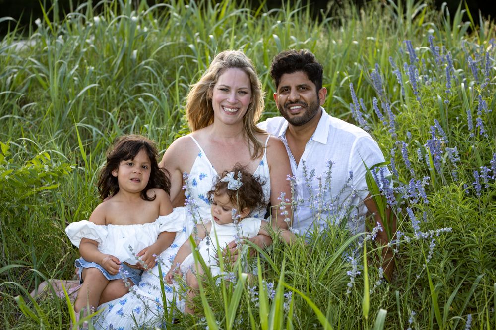 A cheerful family enjoying a photo session in a blooming wildflower meadow on a sunny day.