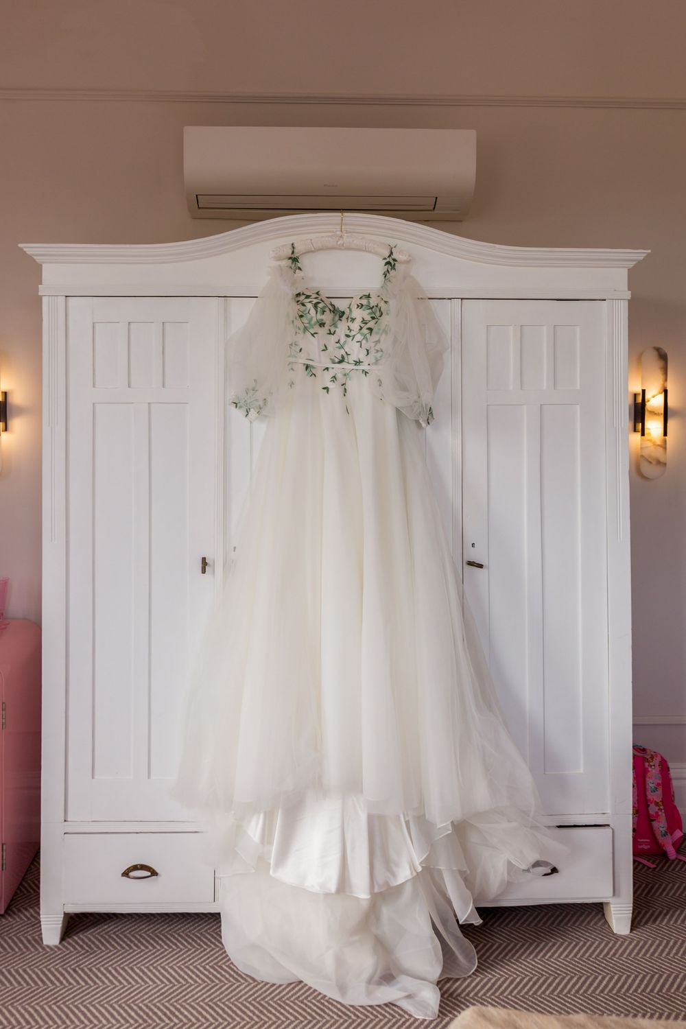 A white wedding dress hangs elegantly from a white wooden armoire in a series of four similar photographs.