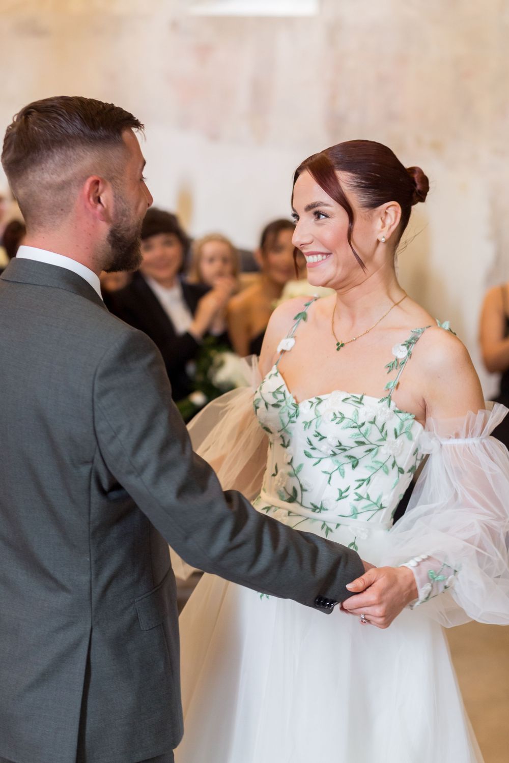 A couple shares a romantic moment during their wedding ceremony in a light-filled venue.