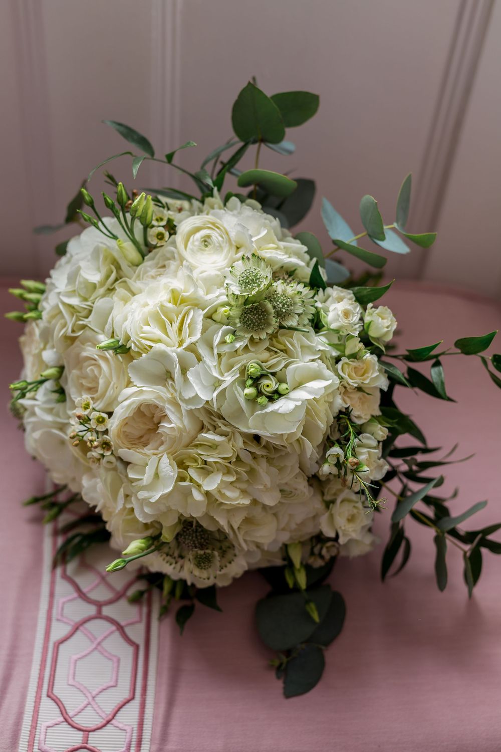 White hydrangea floral arrangement with greenery displayed in a series of photos on a pink surface.