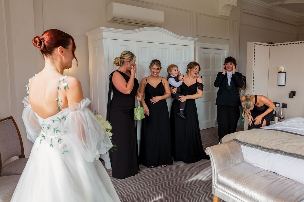 A wedding party in black and white attire poses together in an elegant indoor venue.