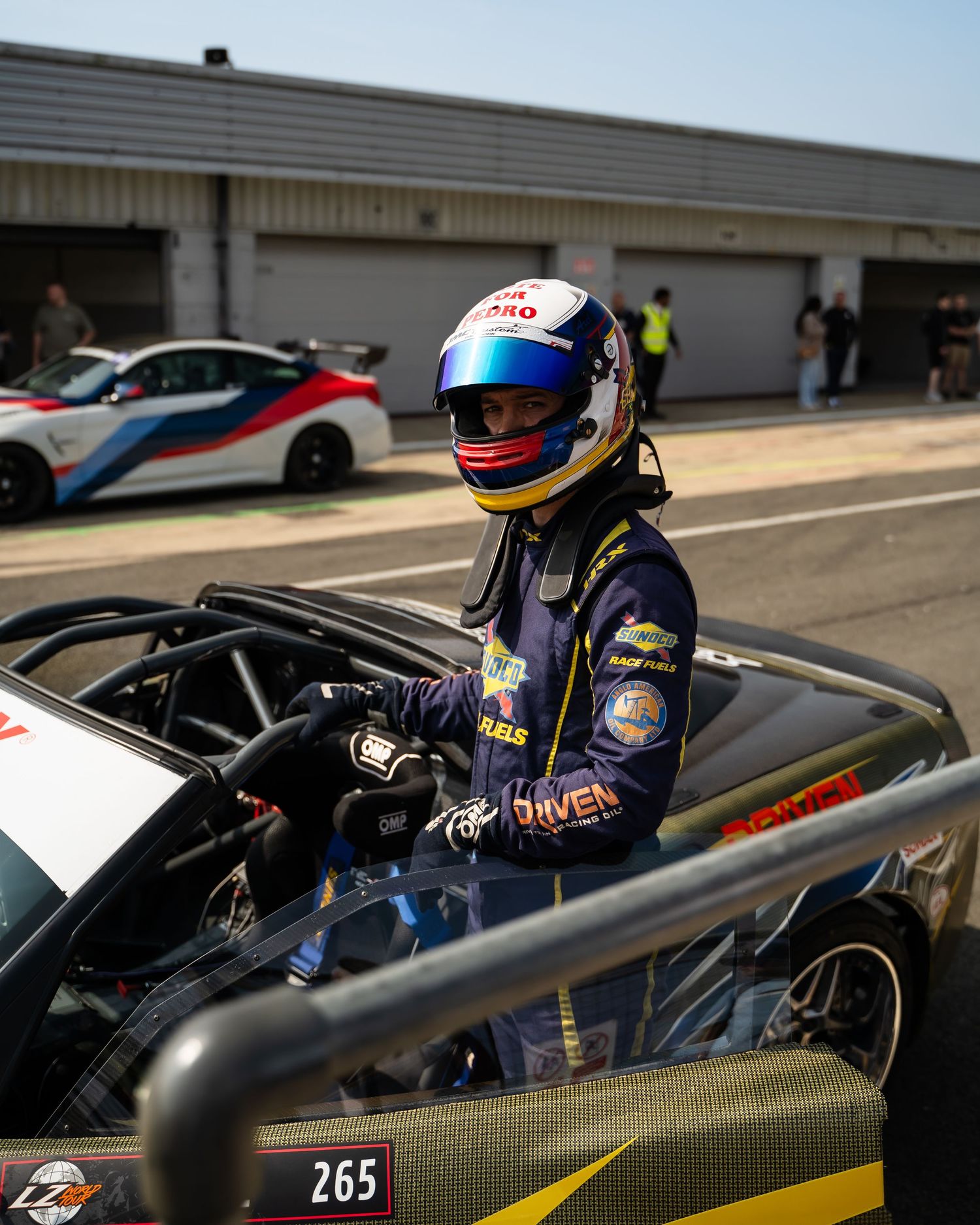 Racing car on track with driver in cockpit during competition.