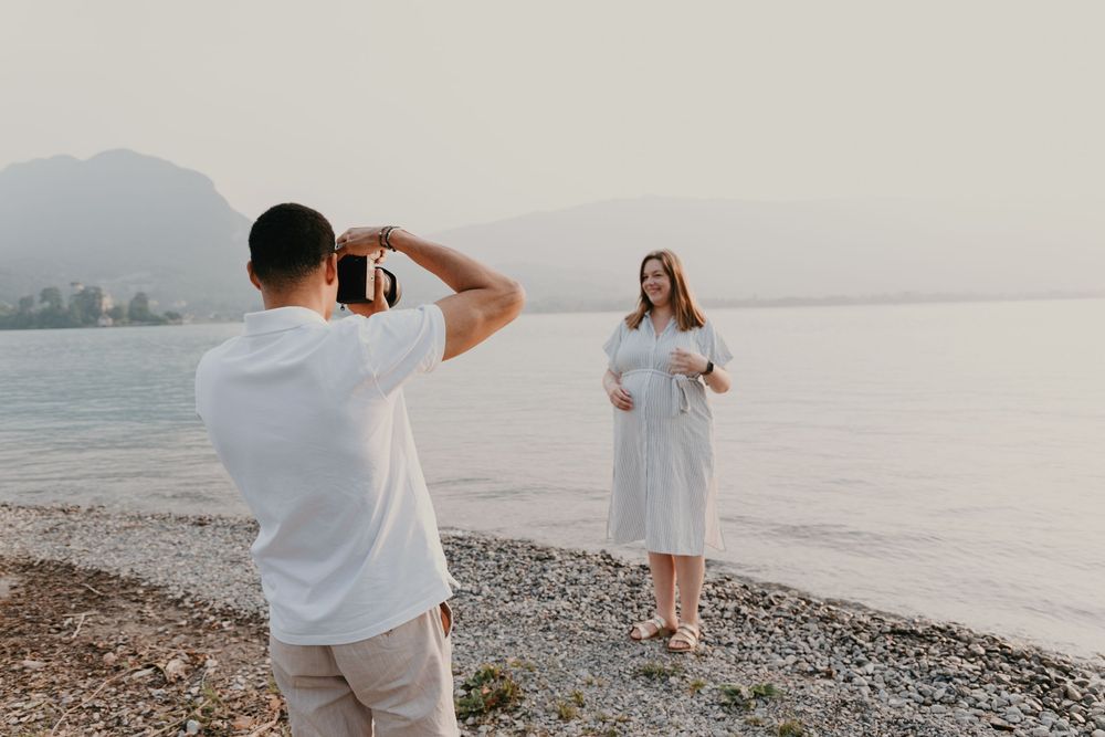 Couple amoureux se prenant en photo au bord du lac d'Annecy lors d'une séance grossesse.
