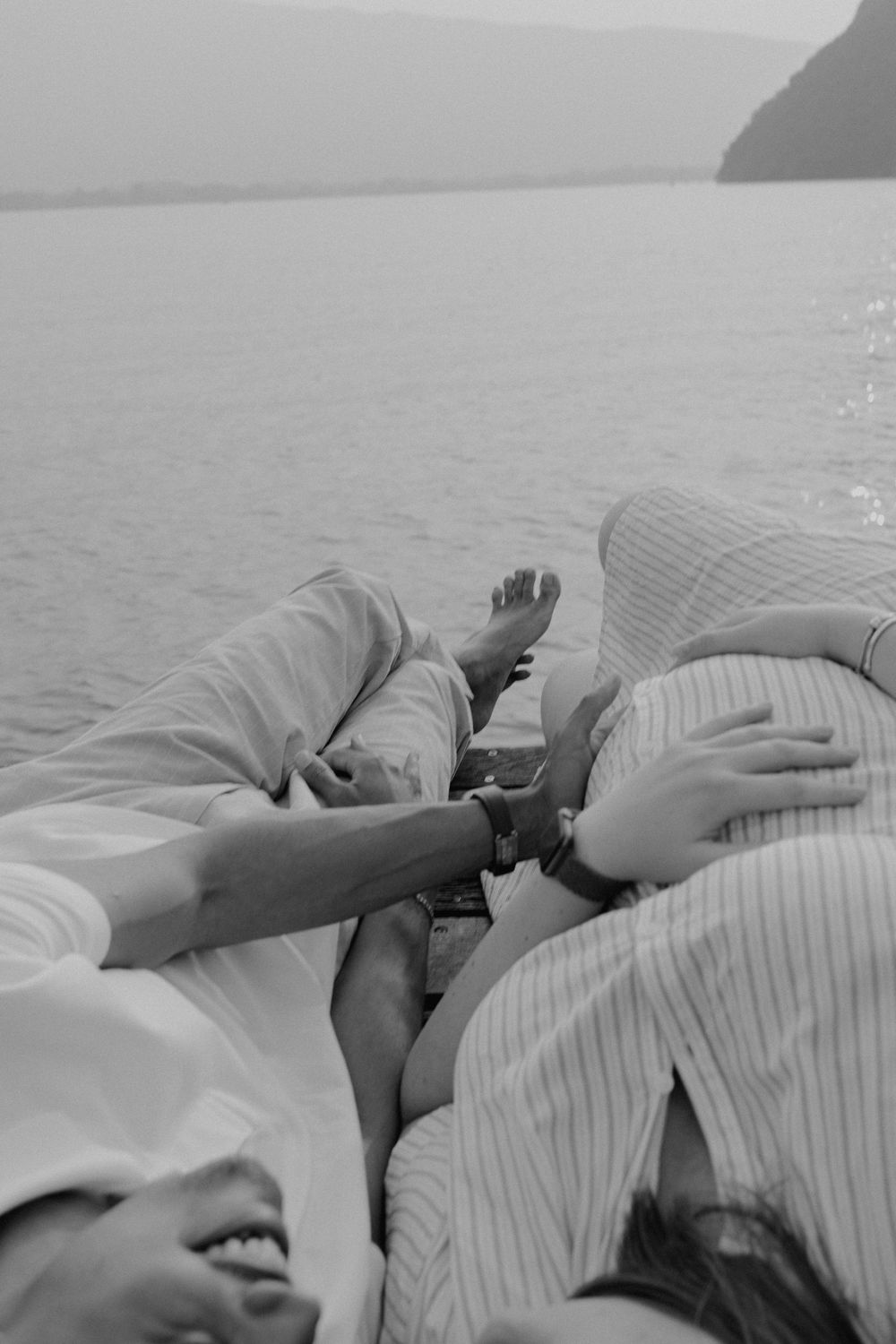 Couple d'amoureux, avec un plan resserré sur le ventre lors d'une séance romantique au bord du lac sur un bateau avec les montagnes