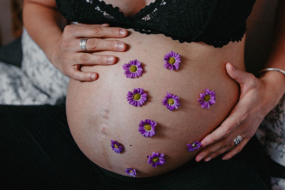 Séance maternité avec des fleurs sur le ventre de la future maman, Photographe grossesse annecy.