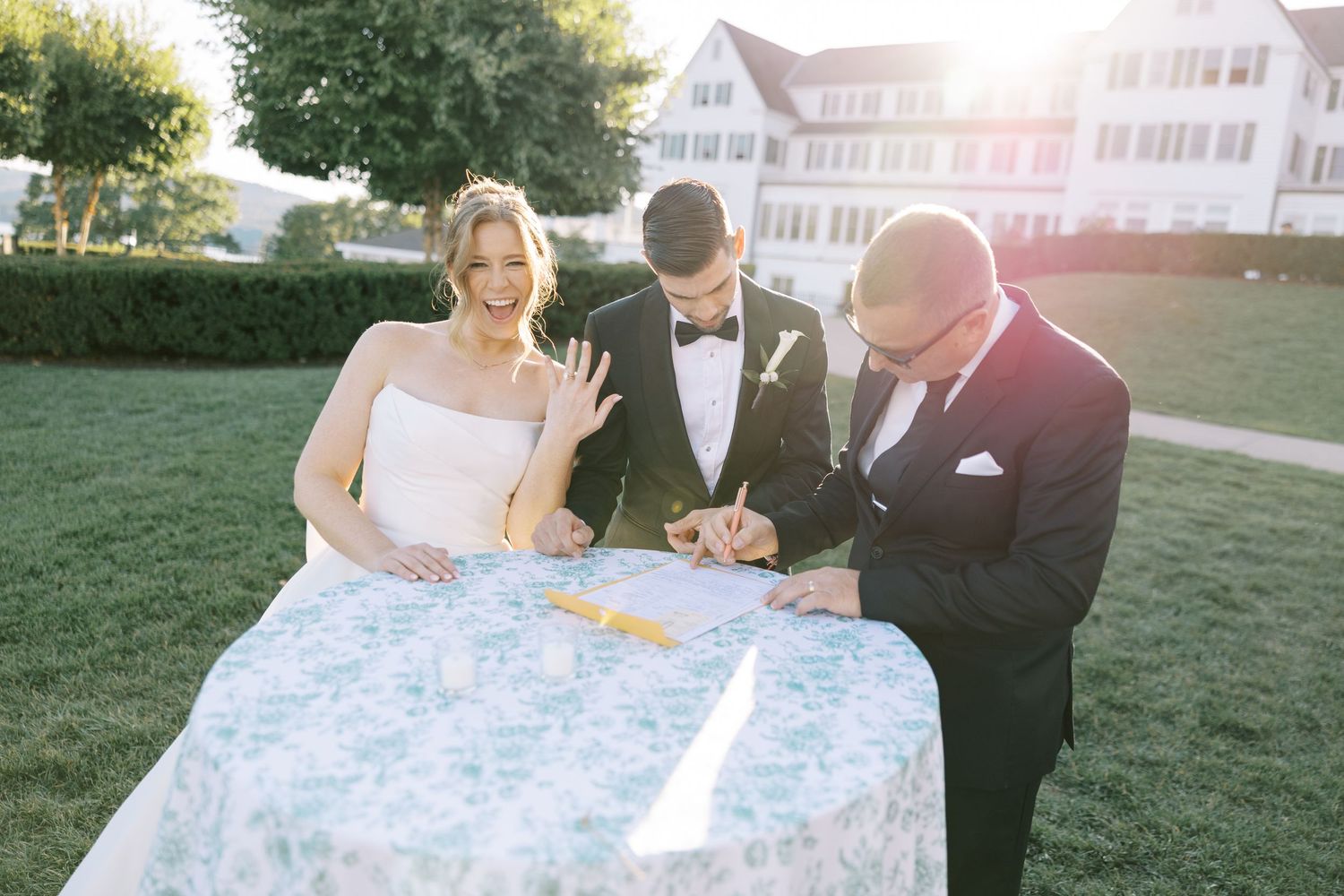 Back view of a bride in an elegant white strapless wedding gown with large bow detail standing on manicured lawn.