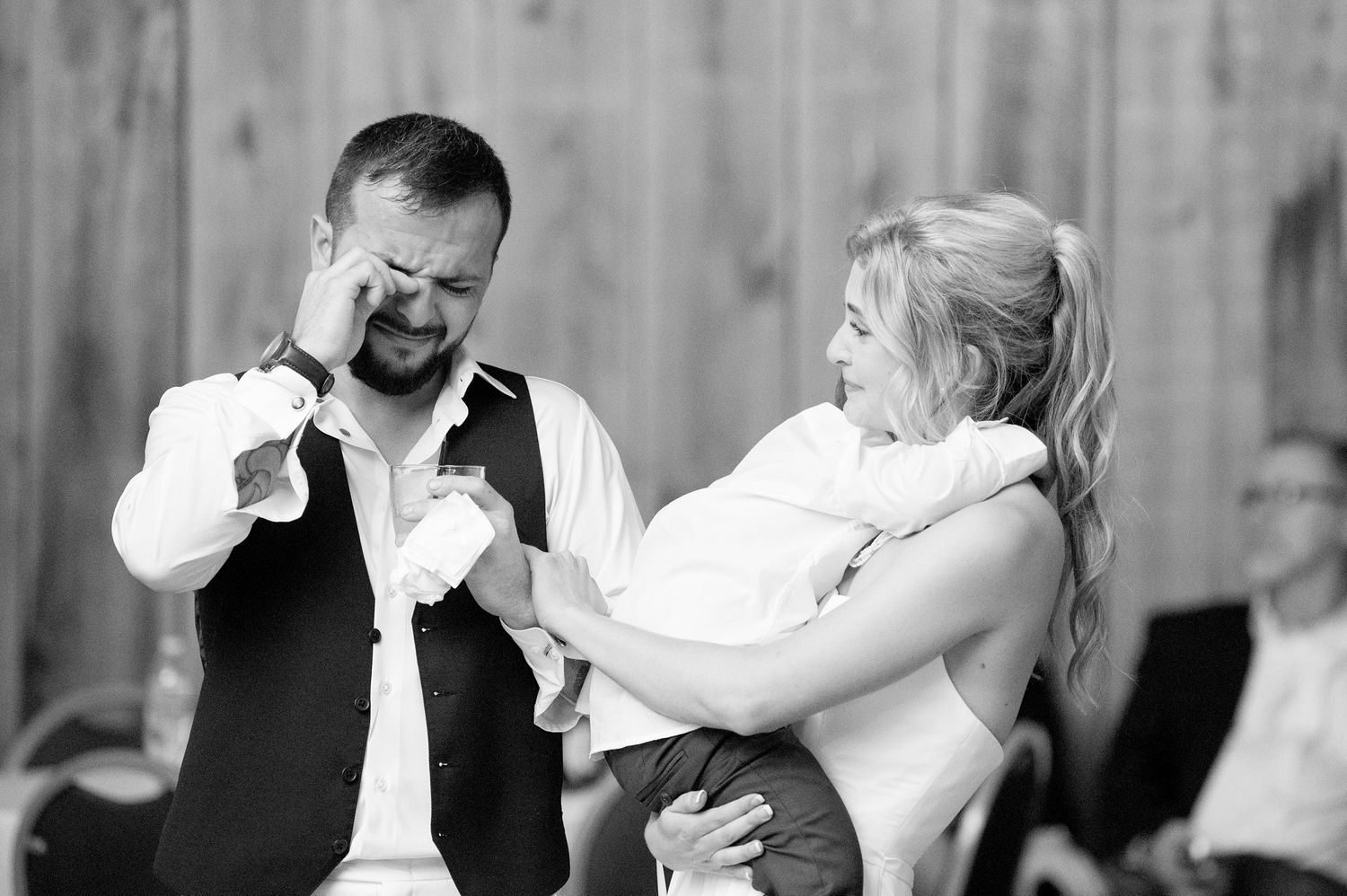 Black and white candid moment of couple laughing during wedding reception.
