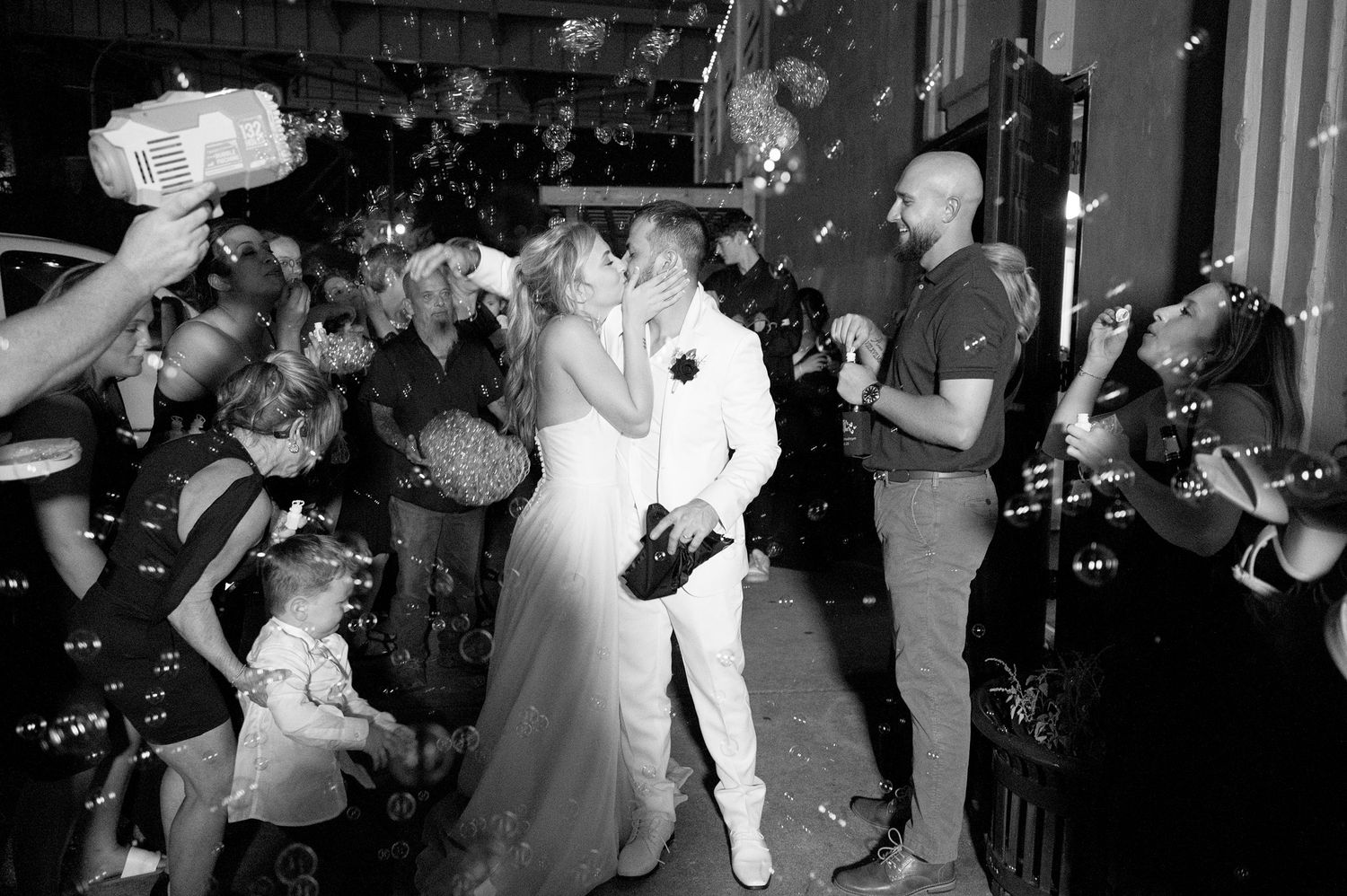 Wedding exit celebration with sparklers and photographers capturing the moment.