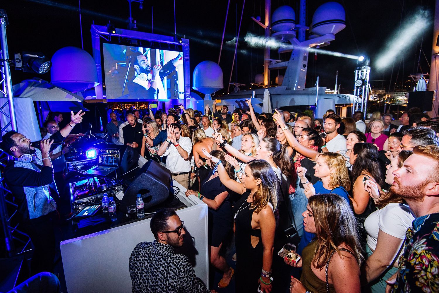 Crowded nightclub scene with dancing people under blue lighting effects.