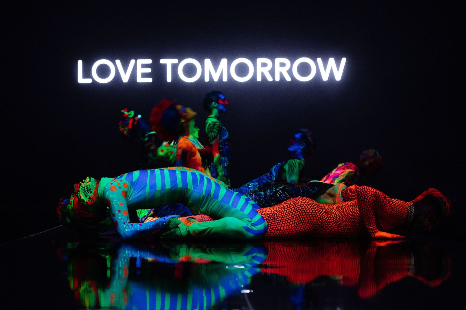 Colorful illuminated art installation with neon text reading 'LOVE TOMORROW' against dark background.