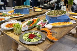 A catering buffet table filled with colorful appetizers, vegetables, and finger foods arranged on various serving platters.