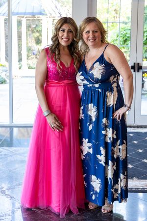 Two beautiful dresses side by side with one bright pink tulle gown and one navy floral pattern dress at a formal event.