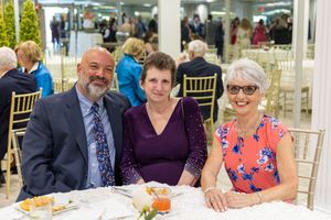 Event guests enjoy a festive gathering at round tables in an elegant banquet hall setting.