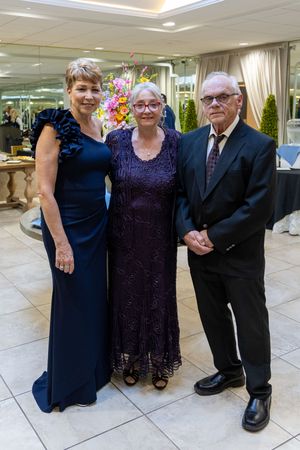 Smiling guests dressed in formal attire pose for photos on a tiled floor at an elegant indoor venue.