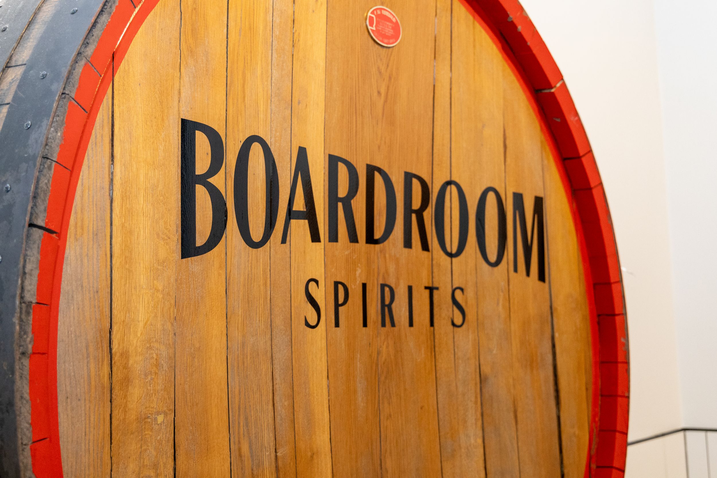 Close-up view of stacked wooden whiskey barrel heads with red metal rings showing distressed wood grain texture.
