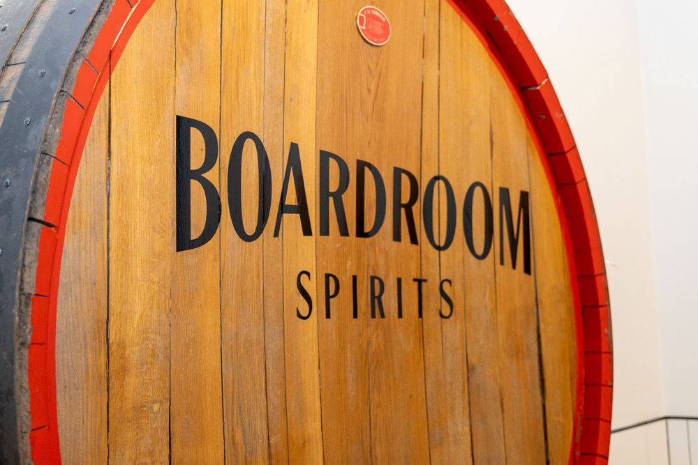Close-up view of stacked wooden whiskey barrel heads with red metal rings showing distressed wood grain texture.
