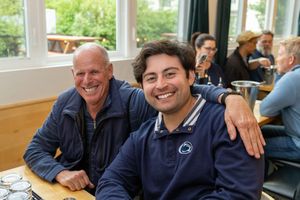 Group of people wearing navy blue apparel seated together at tables in casual dining setting.