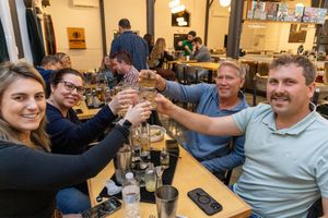 A crowded casual dining scene showing people gathered at a restaurant table enjoying a social gathering at dinner time.