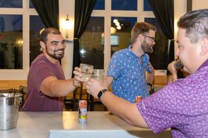 Two people engage in an arm wrestling match at a table while others watch in a restaurant setting.