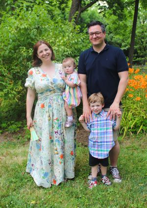 Family portrait outdoors with orange daylilies blooming in the background during summer.