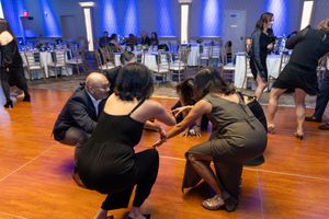 People crouched down in a dance formation on a wooden floor with blue lighting in the background.