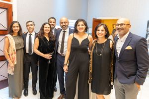 Group of eight elegantly dressed professionals smiling together at a formal gala event.