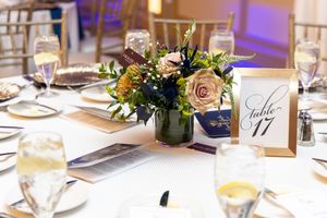 Elegant wedding reception table settings with floral centerpieces, glowing candles and gold table numbers.