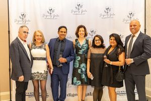 Group of seven elegantly dressed guests posing together at the Dignity Gala charity event.