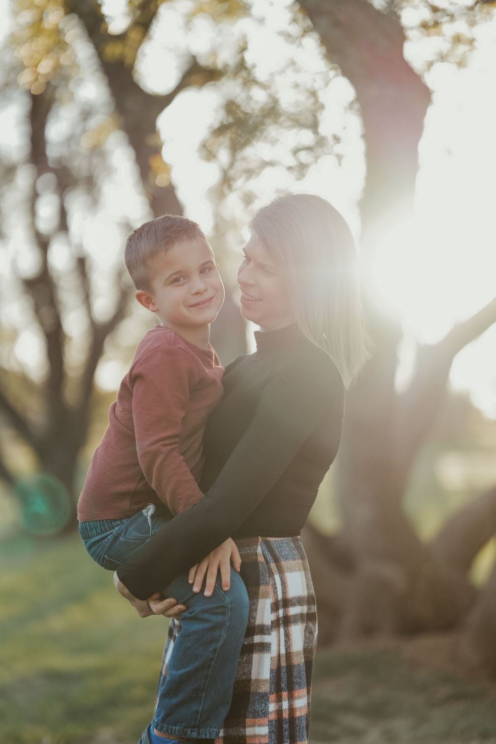 Parent and child sharing tender moment outdoors in golden sunlight.