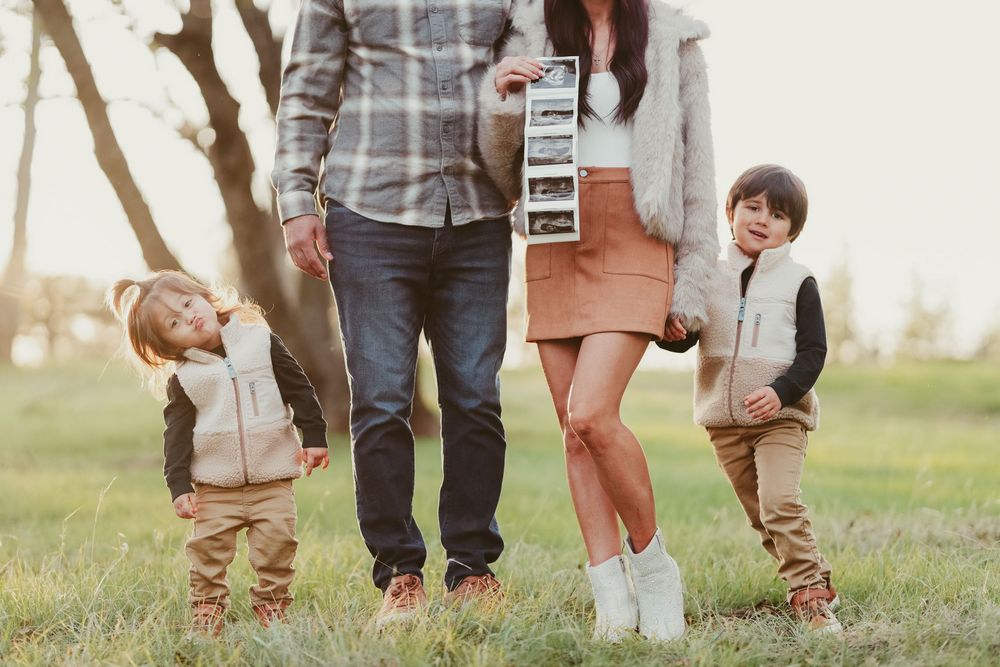 Family members' feet walking together on grass in coordinated brown leather boots.