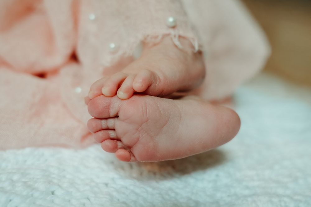 Close-up of tiny baby feet resting on textured blue blanket.