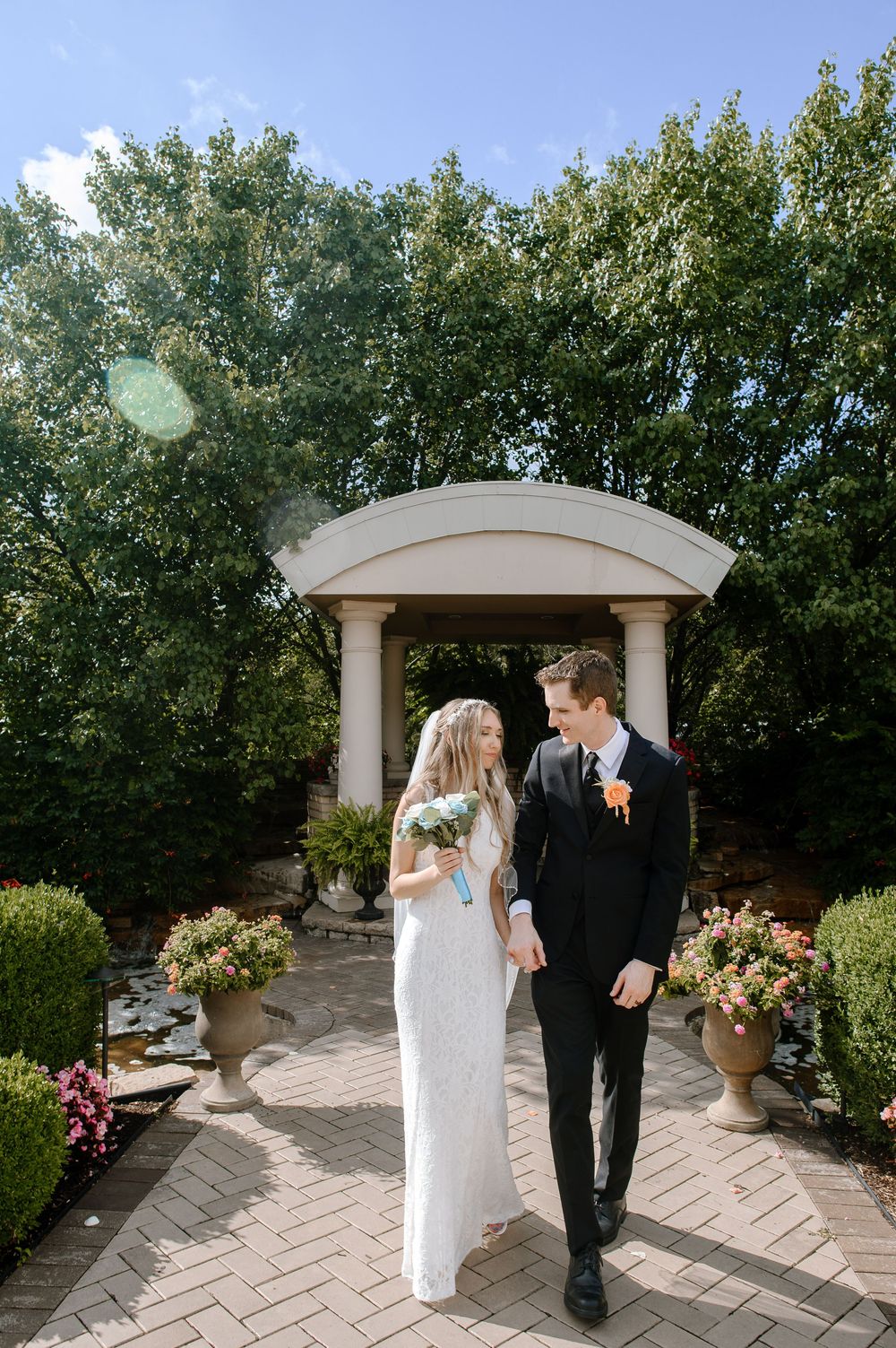 A romantic wedding moment in a garden setting with an arched gazebo and floral arrangements.
