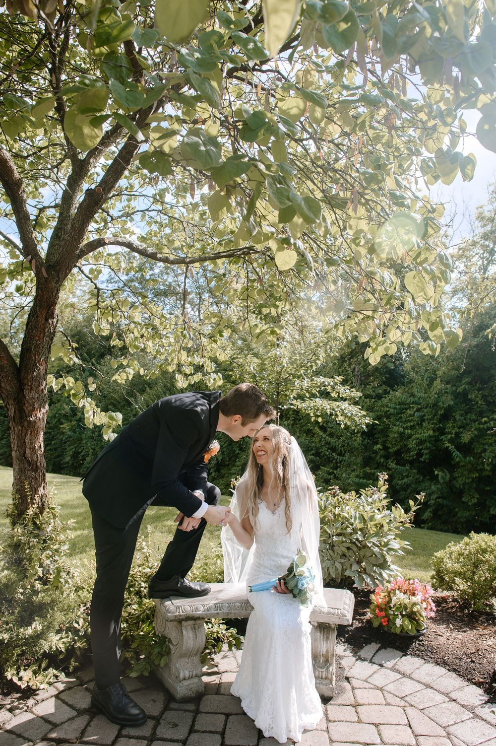 Couple sharing a tender moment under blooming trees in a garden setting.