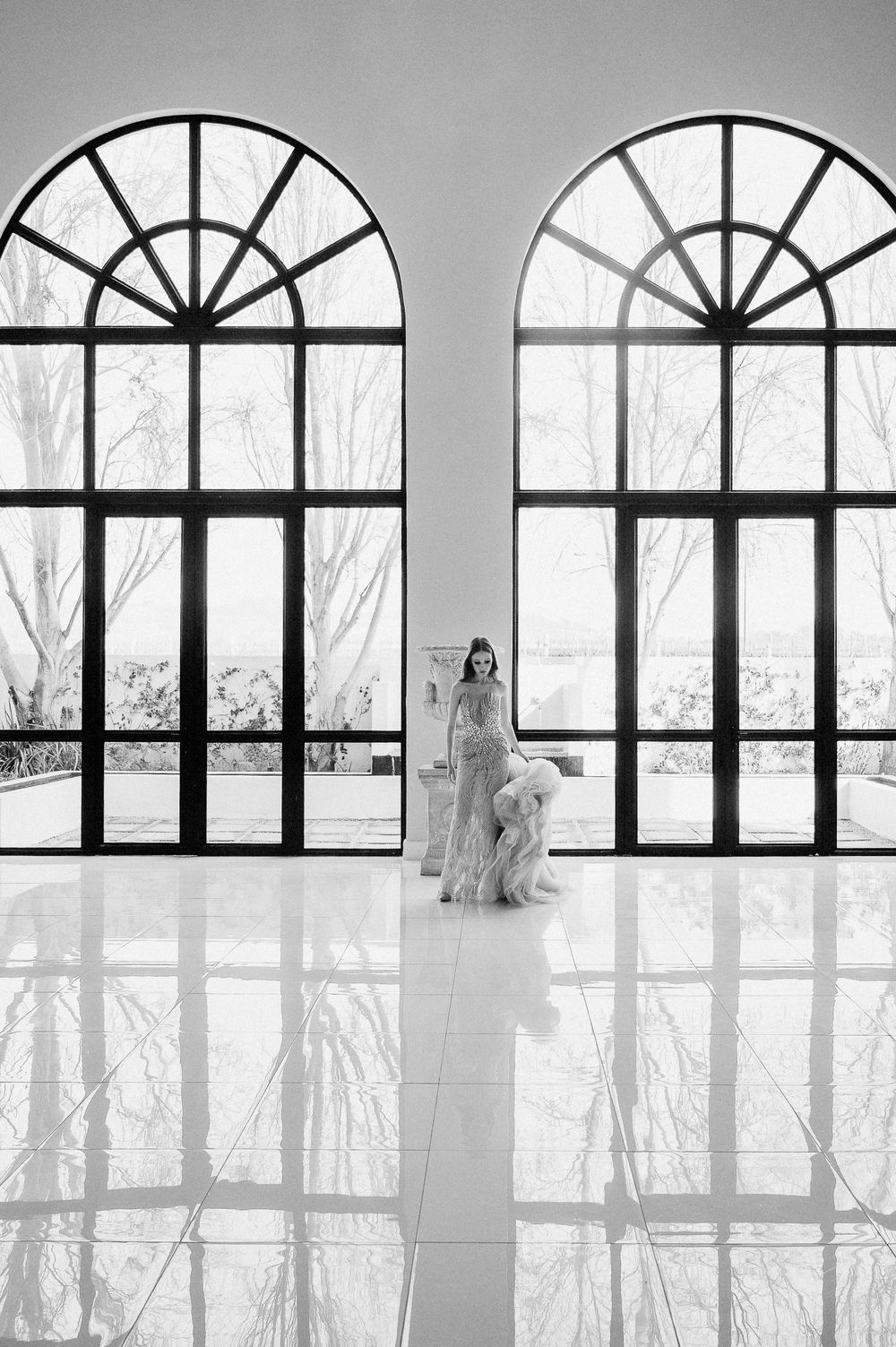 Dramatic arched windows frame a bright interior scene with reflective marble floors.