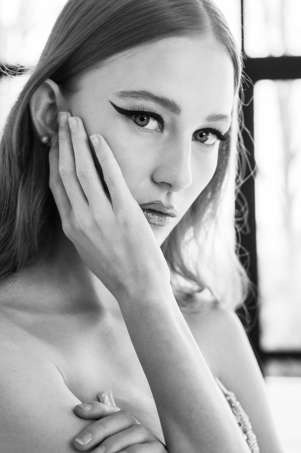 Artistic black and white beauty portrait with dramatic makeup and natural lighting.