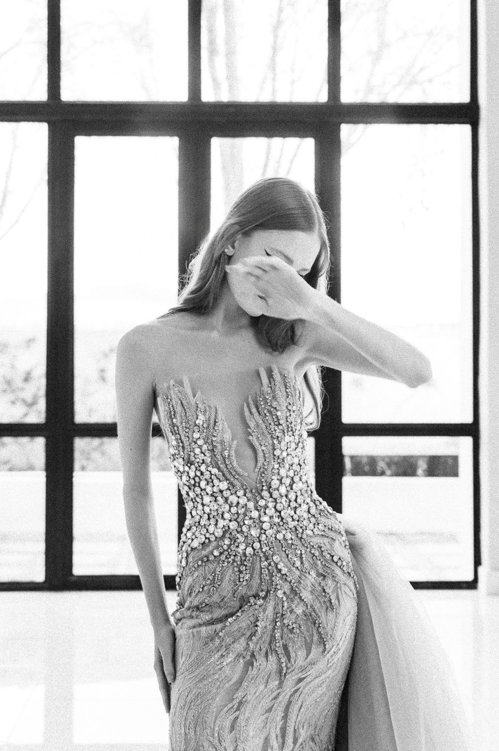 Three black and white images show a diamond-encrusted bustier dress in an elegant window-lit setting.