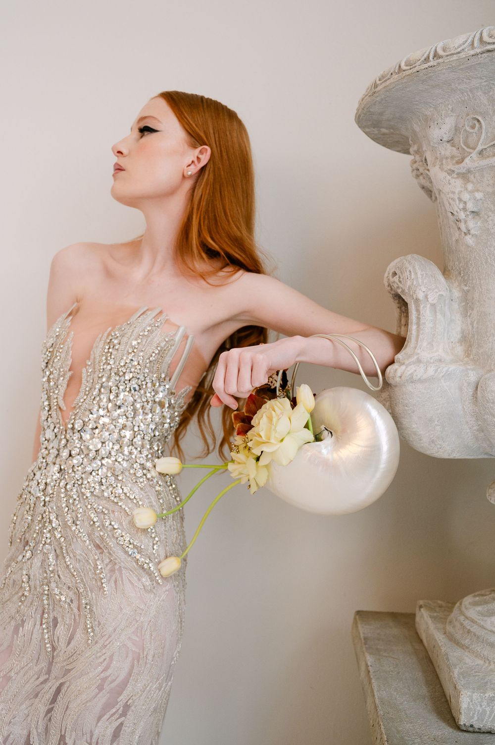 Elegant fashion editorial featuring beaded champagne gown with yellow orchids against classical decor elements.