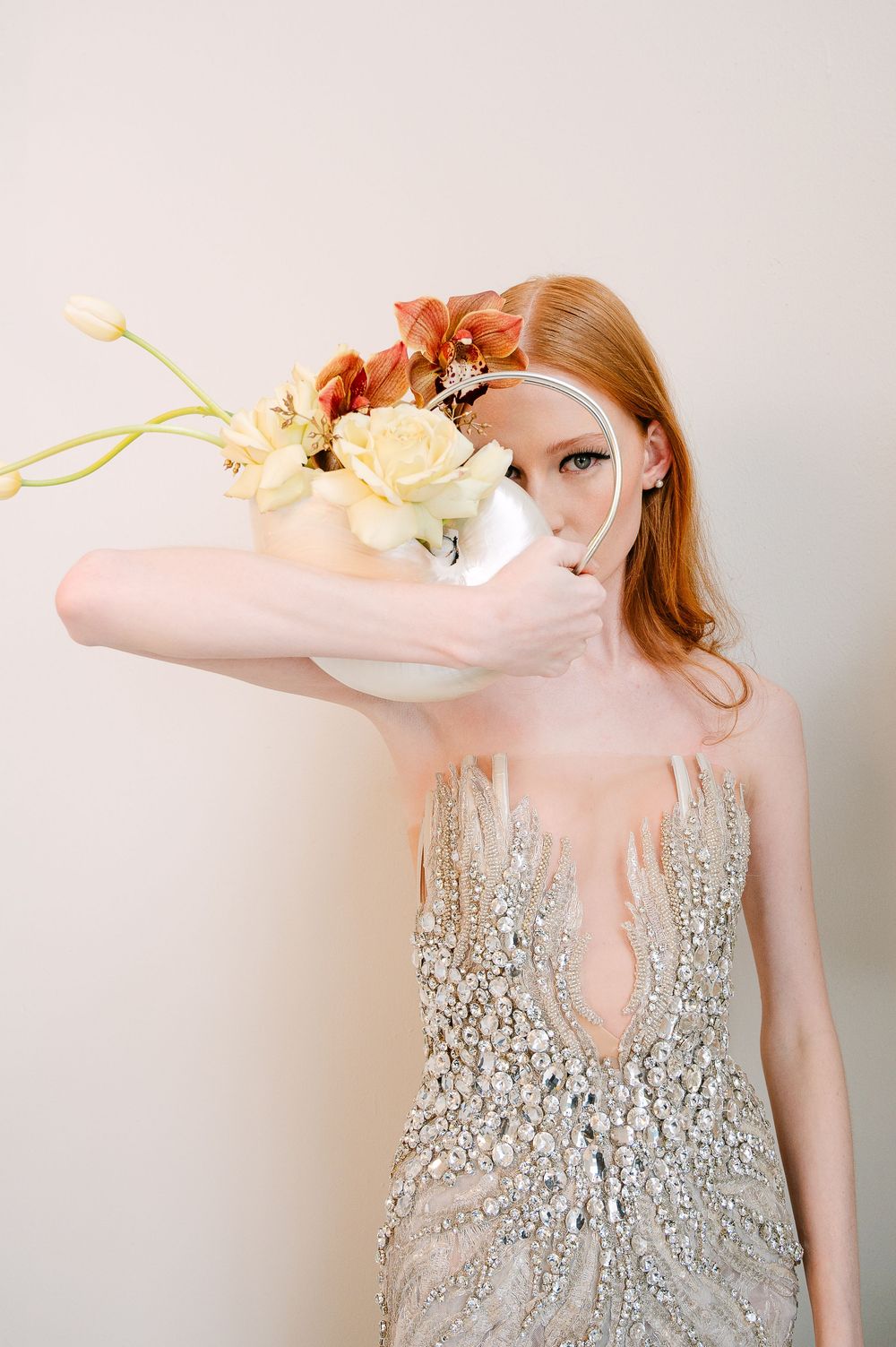 Elegant fashion photoshoot with beaded gown and delicate floral styling in soft natural light.