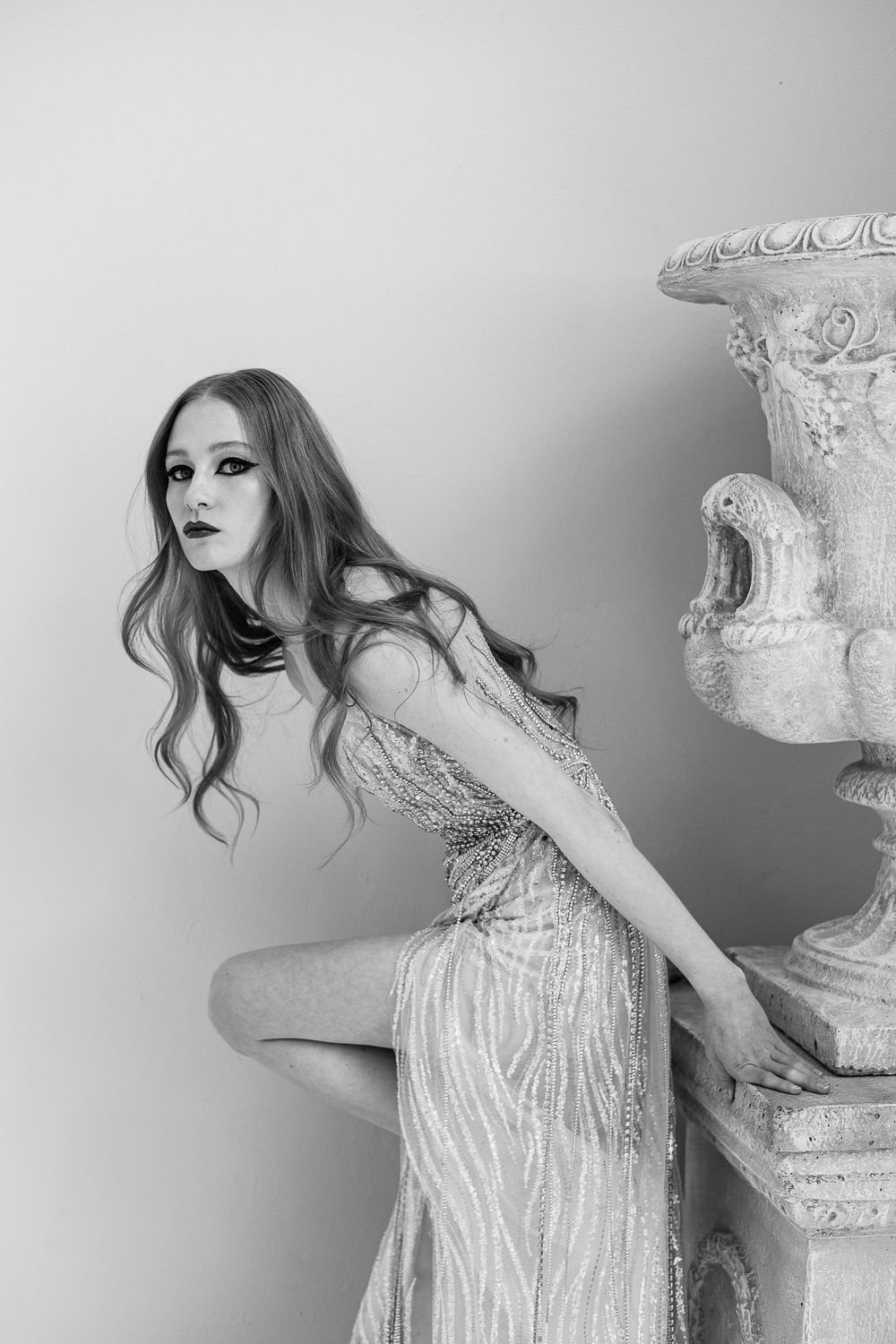 Black and white artistic portrait of someone in an elegant sequined gown with flowing hair in a romantic pose.