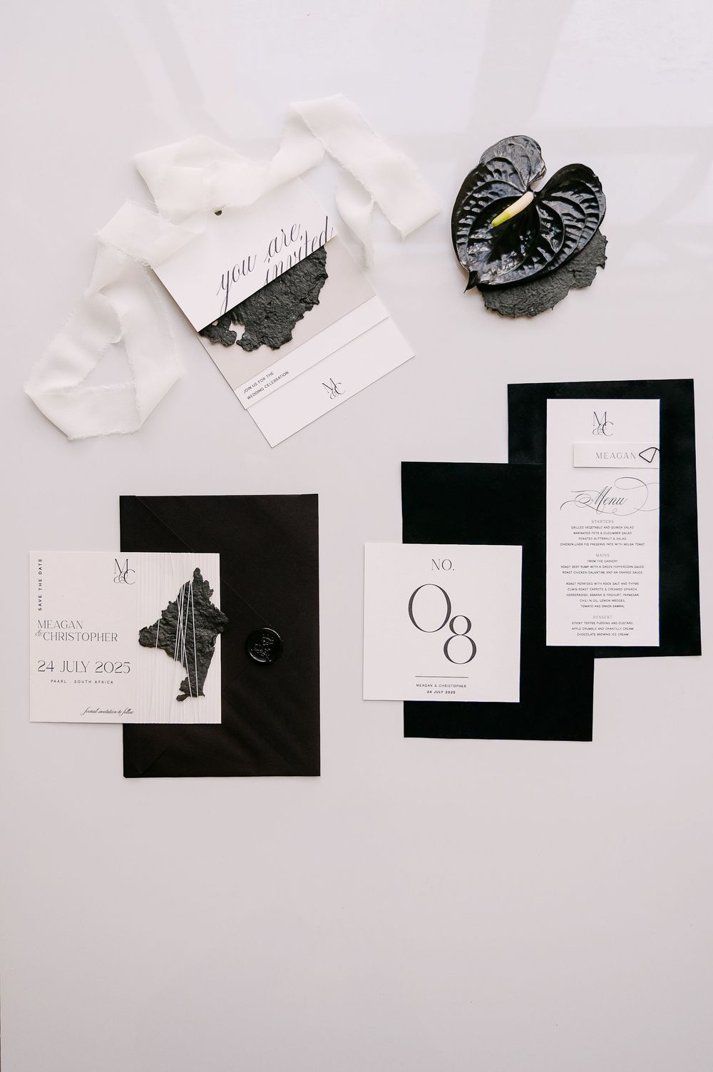 Modern black and white wedding stationery pieces displayed in flat lay composition.