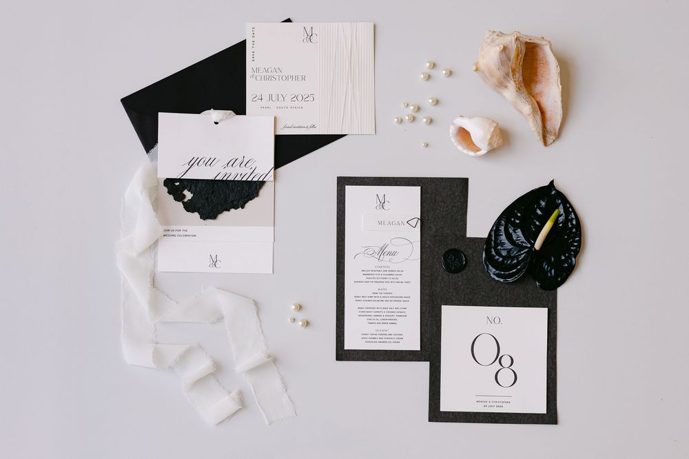 Minimalist flat lay of black and white wedding stationery and paper elements.