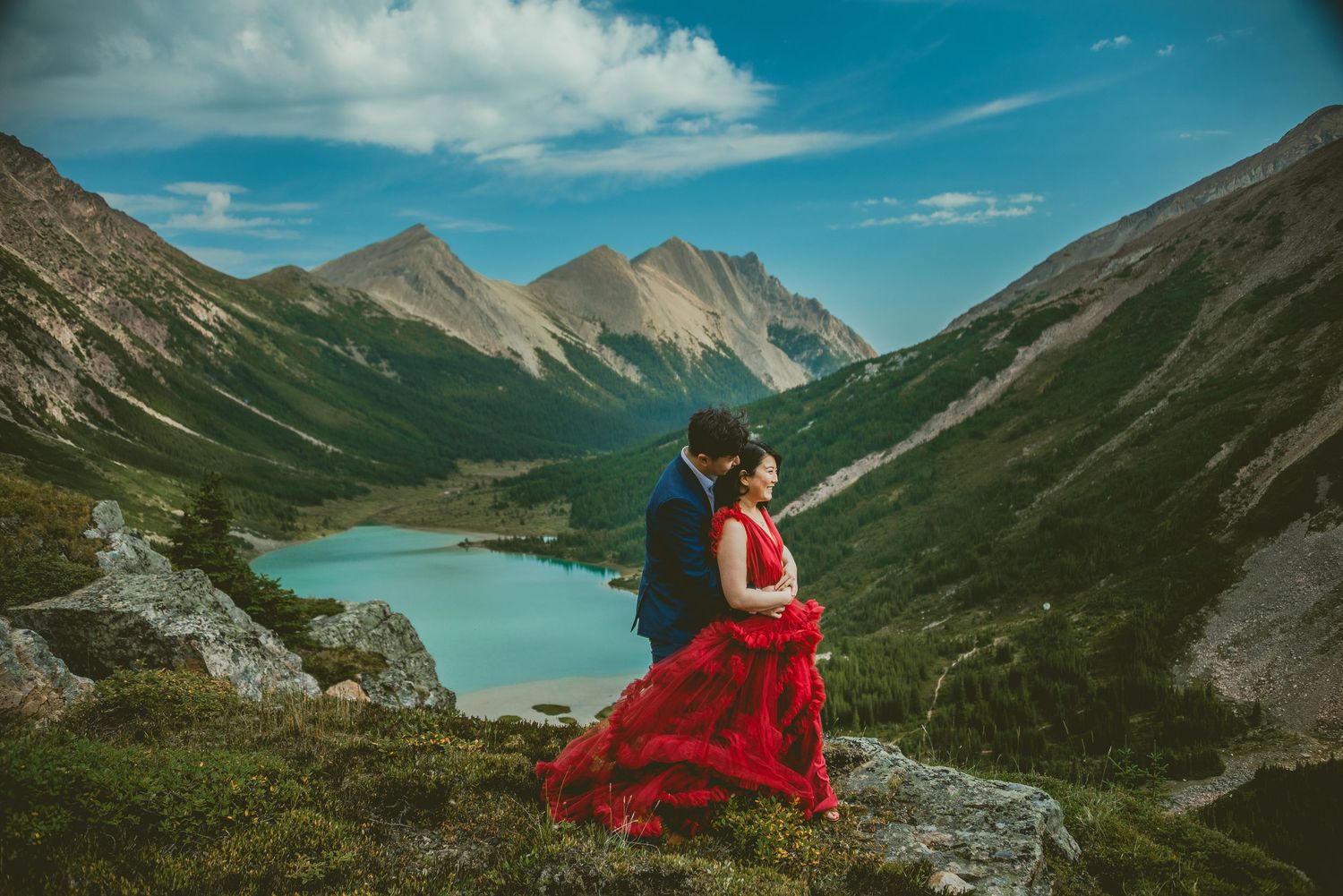 Stunning mountain landscape with turquoise lake and dramatic cloudy sky in the background. Alberta Helicopter Elopement Photographer