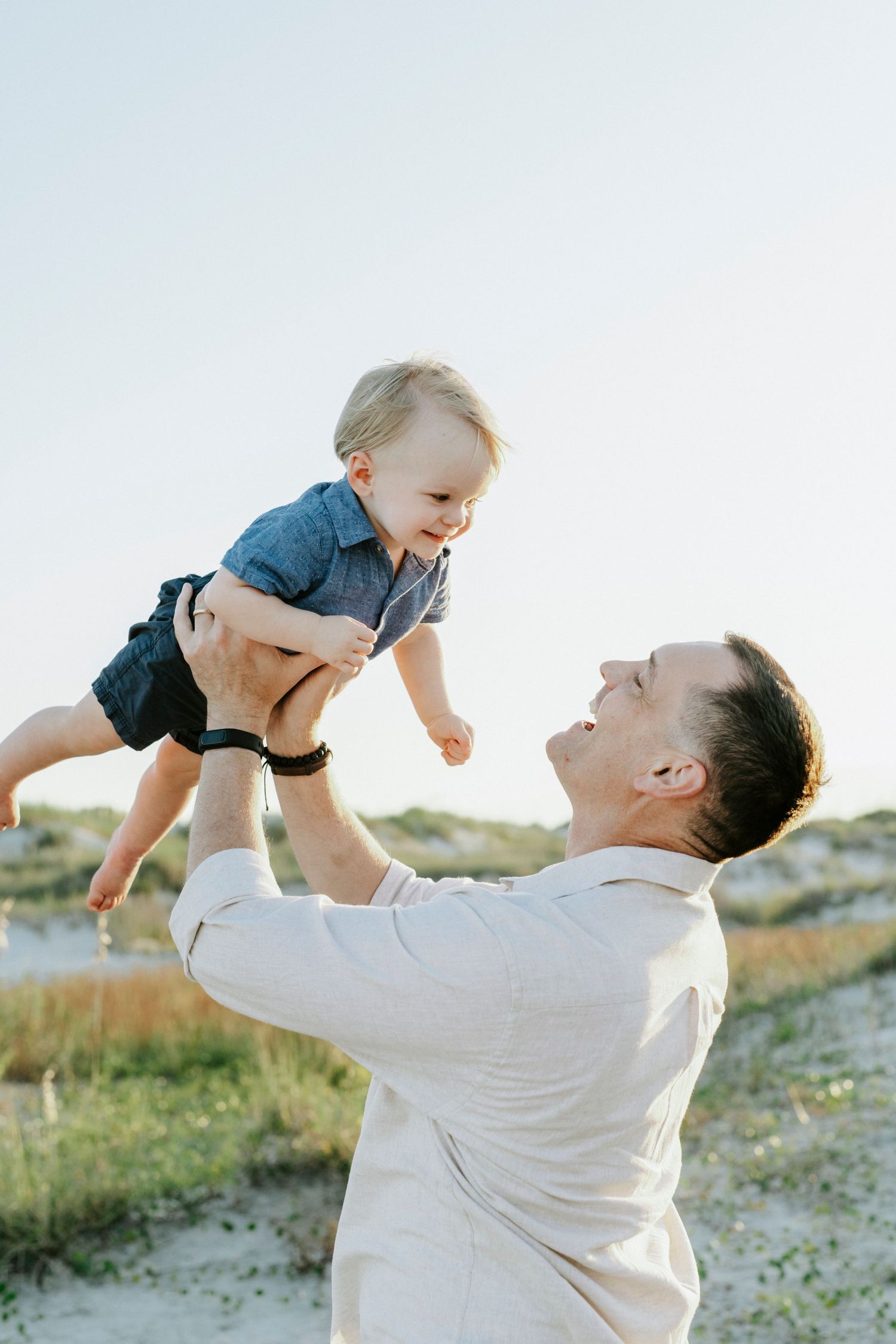 A joyful moment between parent and small child playing together on the beach at sunset.