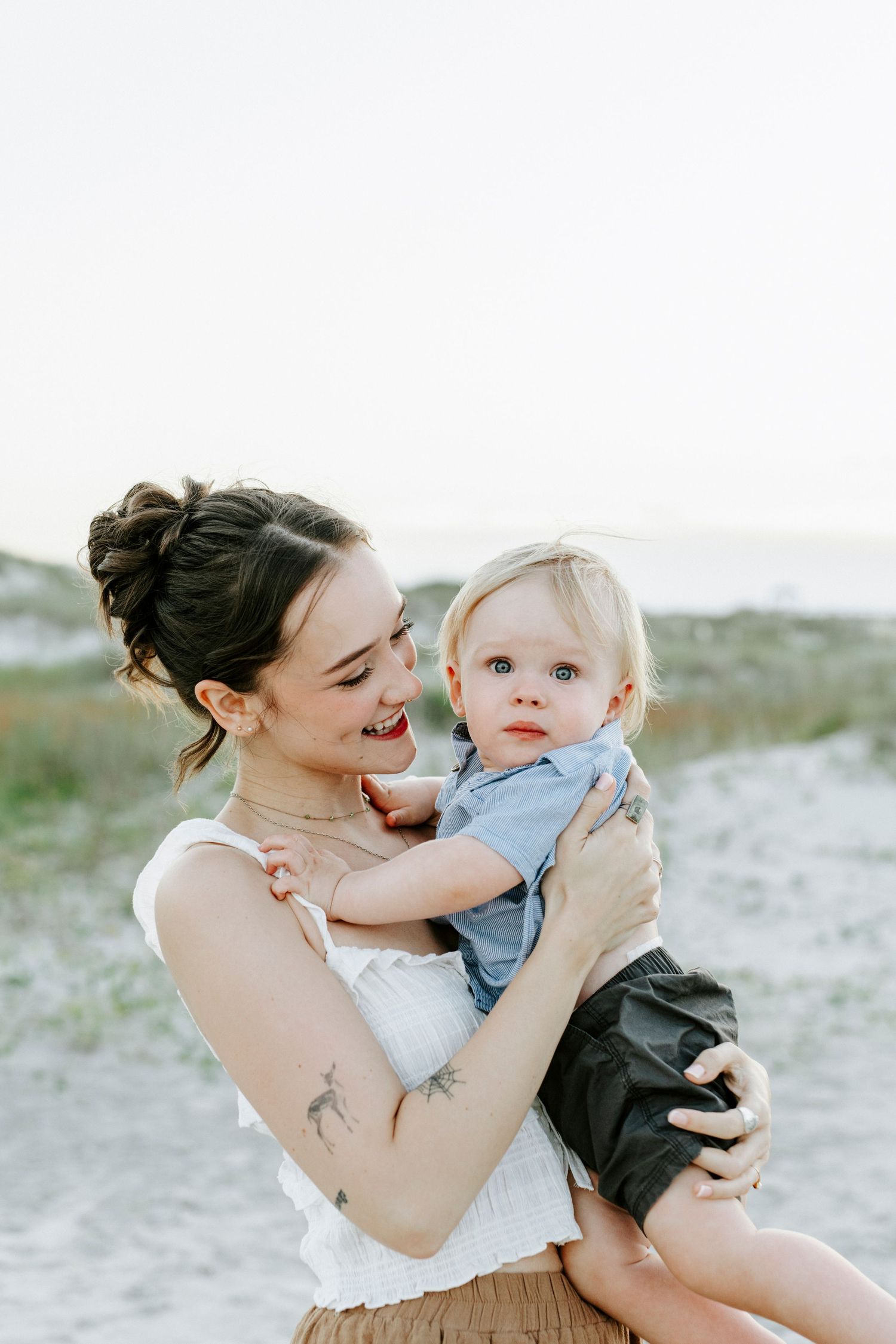 Portrait of mother and child embracing on a beach with soft lighting.