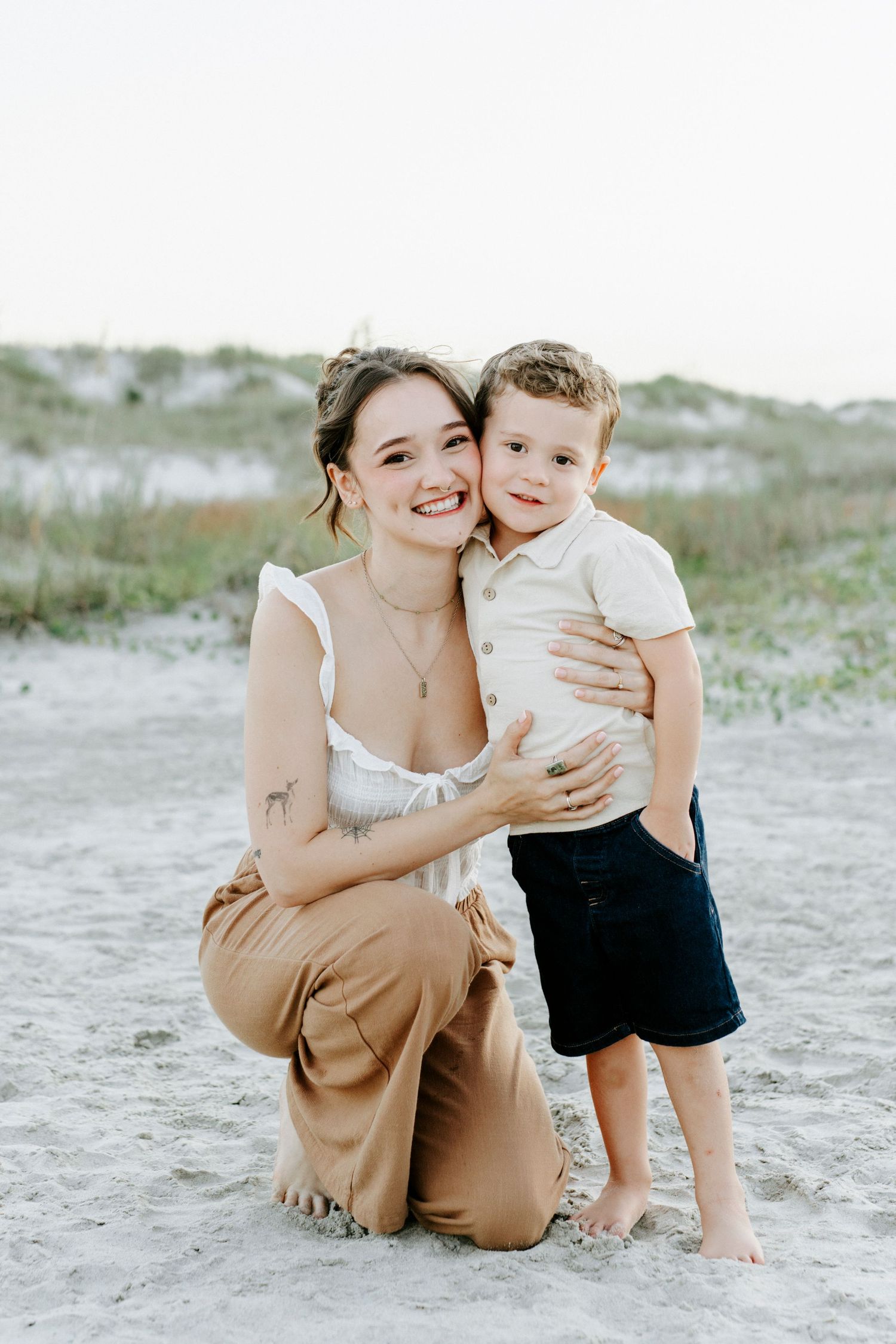 A tender moment between parent and child on a sandy beach with soft, muted tones.