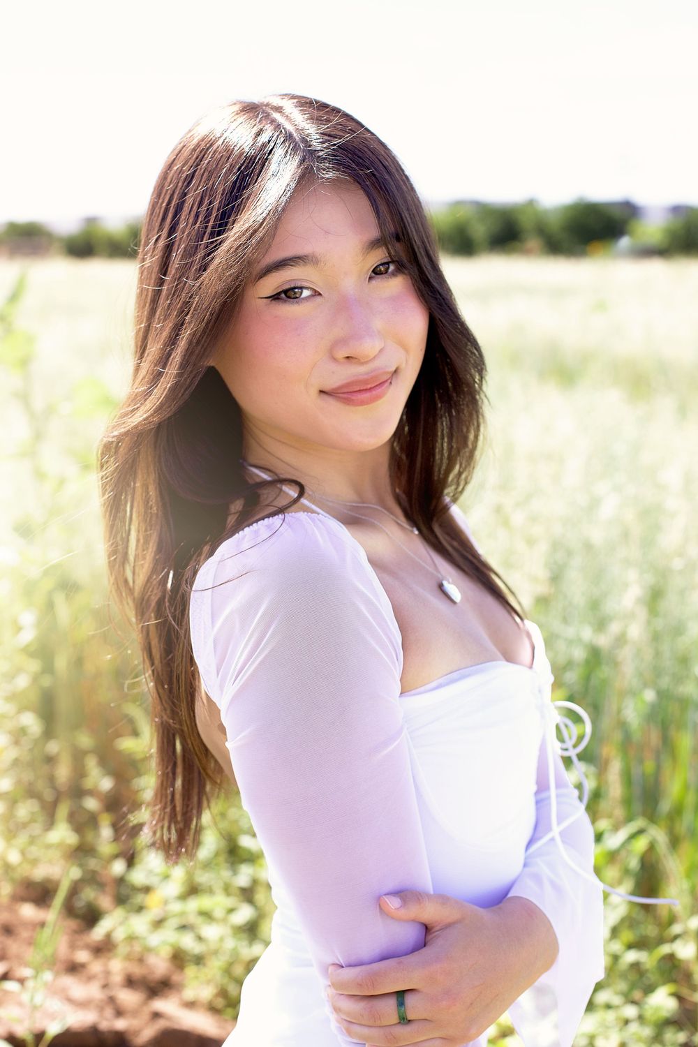 Outdoor portrait session in a natural field setting wearing a white dress.